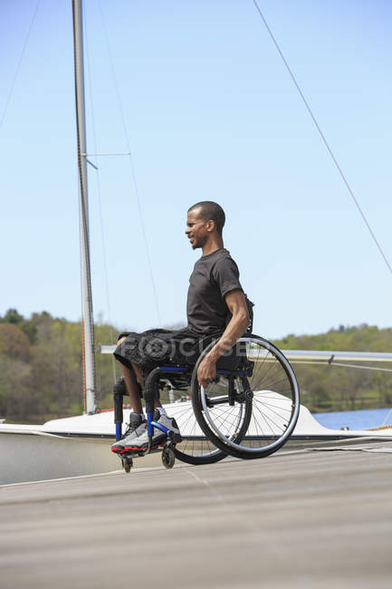 Man in a wheelchair who had Spinal Meningitis at a sailing dock — Stock Photo