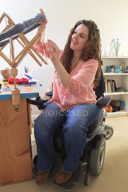 Woman with Muscular Dystrophy working with her umbrella yarn winder on her power chair — Stock Photo