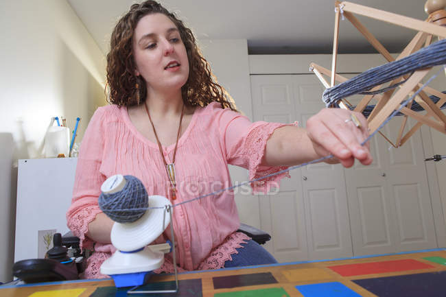 Femme atteinte de dystrophie musculaire travaillant avec son enrouleur de fil de parapluie sur sa chaise de puissance — Photo de stock