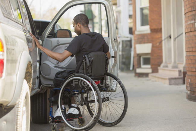 Uomo su una sedia a rotelle con meningite spinale che entrava nel suo veicolo accessibile — Foto stock
