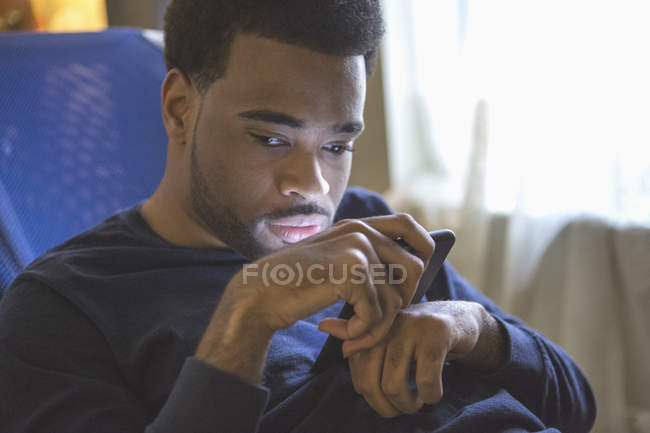 Uomo afroamericano con paralisi cerebrale usando il cellulare a casa — Foto stock