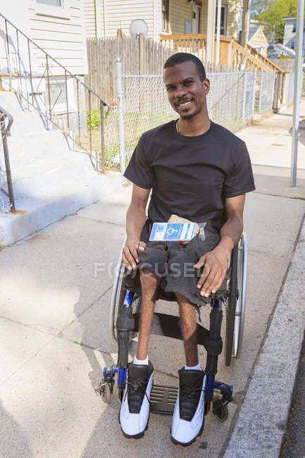 Man in a wheelchair who had Spinal Meningitis on the city street — Stock Photo
