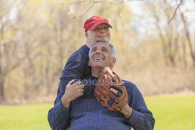 Father with Spinal Cord Injury and son with Down Syndrome about to play baseball in park — Stock Photo