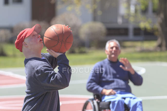Отец и сын с синдромом Дауна играют в баскетбол — стоковое фото
