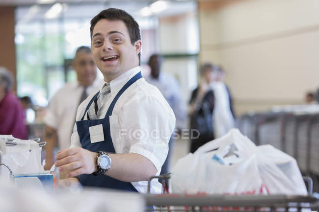Людина з синдромом Дауна працює в продуктовому магазині — стокове фото
