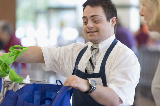 Man with Down Syndrome working at a grocery store — Stock Photo