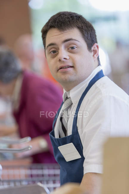 Hombre con Síndrome de Down trabajando en una tienda de comestibles - foto de stock