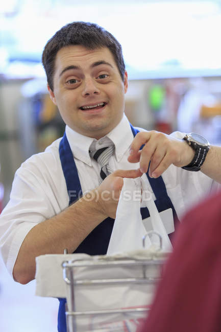 Hombre con Síndrome de Down trabajando en una tienda de comestibles - foto de stock