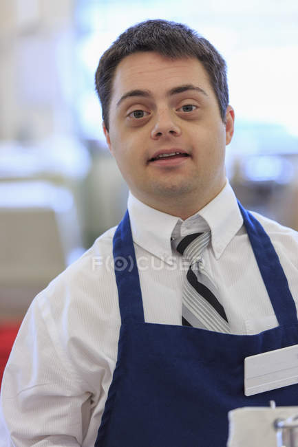 Человек с синдромом Дауна работает в продуктовом магазине — стоковое фото
