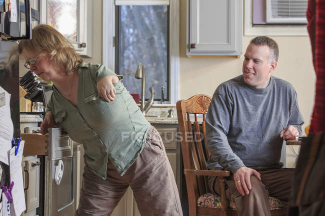 Mujer con Síndrome de TAR usando un cajón de la cocina con su marido - foto de stock