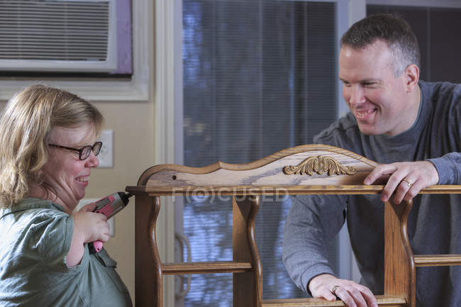 Mulher com Síndrome de TAR usando uma serra elétrica com o marido — Fotografia de Stock