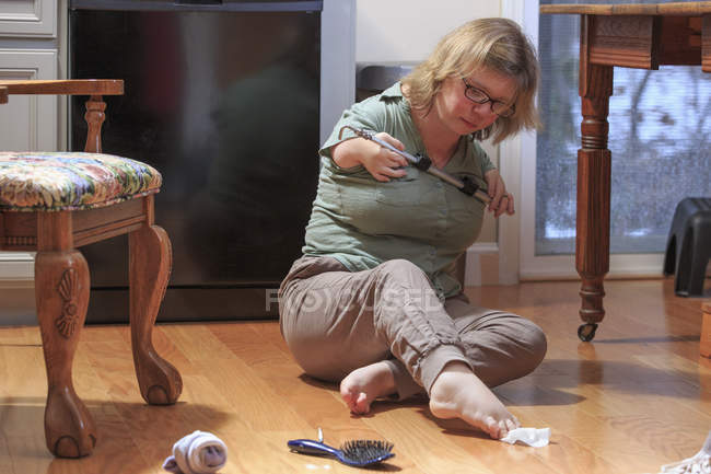 Woman with TAR Syndrome picking up an item with her feet — Stock Photo