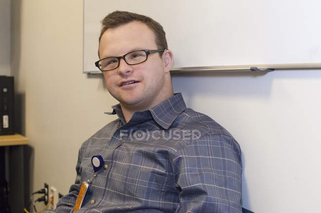 Retrato del trabajador de ayuda hospitalaria con síndrome de Down que trabaja en la oficina - foto de stock