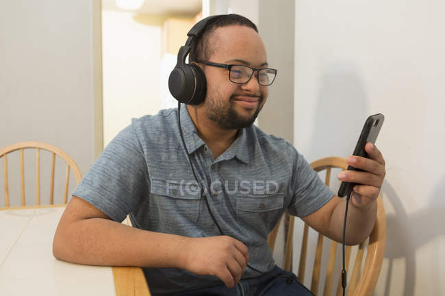 Heureux Afro-Américain trisomique écoutant de la musique avec des écouteurs à la maison — Photo de stock