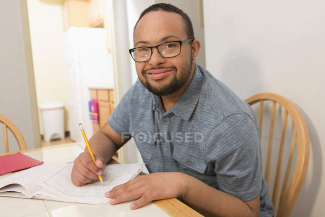 Happy African American man with Down Syndrome studying at home — Stock Photo