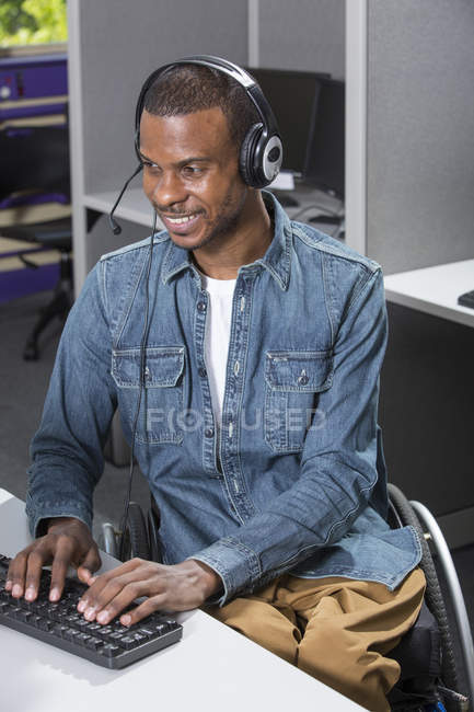 Man who had Spinal Meningitis in a wheelchair working in a call center — Stock Photo