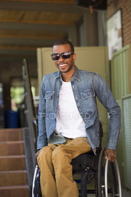 Man who had Spinal Meningitis in a wheelchair looking exited on a stair lift in an office — Stock Photo