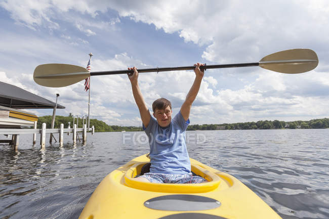 Счастливый молодой человек с синдромом Дауна использует байдарку в озере — стоковое фото