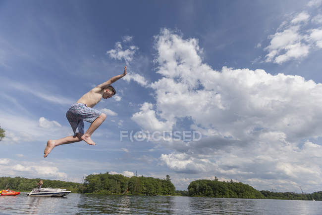 Young man with Down Syndrome jumping into a lake — Stock Photo