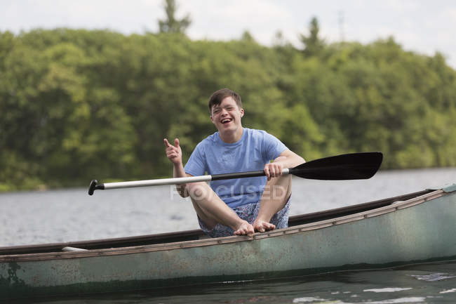 Jovem feliz com Síndrome de Down remando uma canoa em um lago — Fotografia de Stock