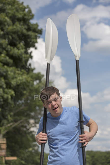Un joven con síndrome de Down se prepara para usar un bote en un muelle - foto de stock