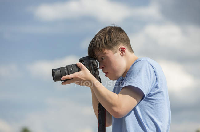 Joven con Síndrome de Down fotografiando con cámara - foto de stock