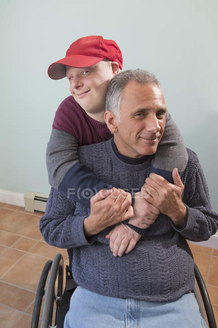 Pai com lesão medular e filho com síndrome de Down juntos em casa — Fotografia de Stock