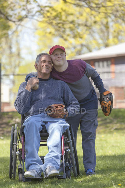 Père avec blessure à la moelle épinière et fils avec trisomie 21 sur le point de jouer au baseball dans le parc — Photo de stock