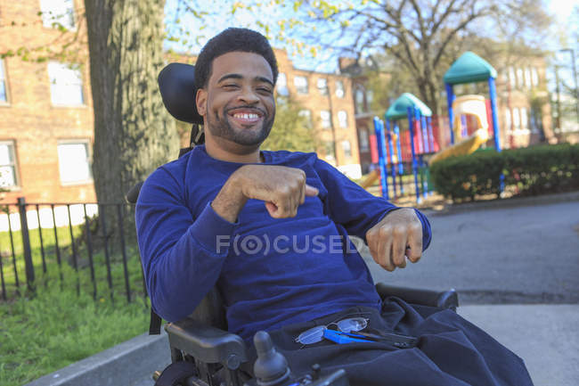 Felice uomo afroamericano con paralisi cerebrale utilizzando la sua sedia a rotelle potere al di fuori — Foto stock