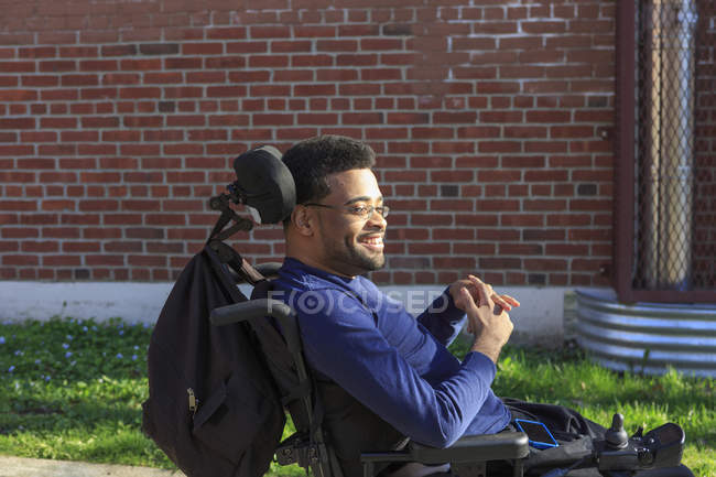 Felice uomo afroamericano con paralisi cerebrale utilizzando la sua sedia a rotelle potere al di fuori — Foto stock