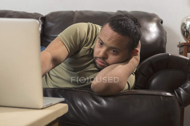 Щасливий афроамериканець людина з синдромом Дауна за допомогою ноутбука вдома — стокове фото