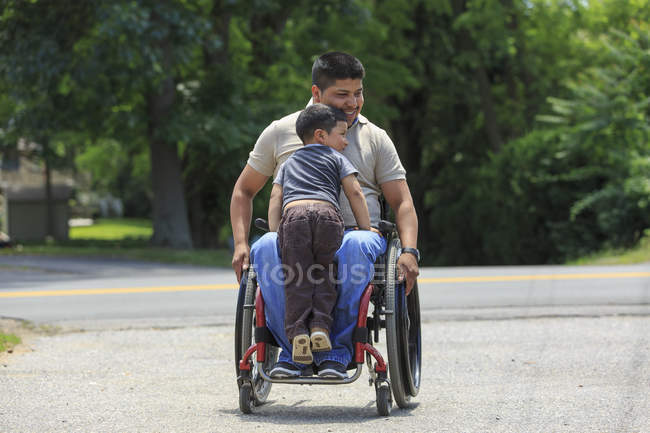 Латиноамериканец с травмой спинного мозга в инвалидном кресле со своим сыном — стоковое фото