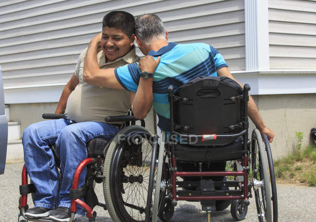 Amici con lesioni del midollo spinale in sedie a rotelle salutarsi — Foto stock