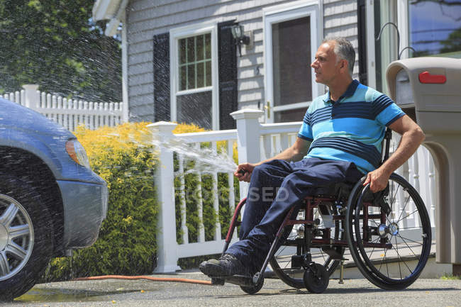 Mann mit Querschnittslähmung im Rollstuhl wäscht sein behindertengerechtes Auto — Stockfoto