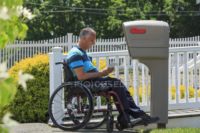 Uomo con una lesione al midollo spinale sulla sedia a rotelle a ricevere la sua posta — Foto stock