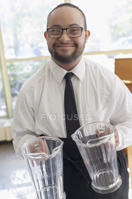 Hombre afroamericano con síndrome de Down como camarero trabajando en restaurante - foto de stock