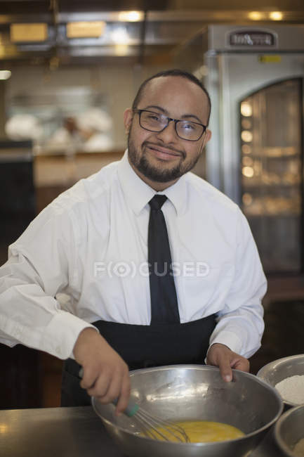 Happy African American man with Down Syndrome as a chef cooking in commercial kitchen — Stock Photo