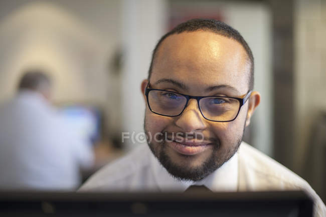 Happy African American man with Down Syndrome as a waiter taking reservations in the computer — Stock Photo