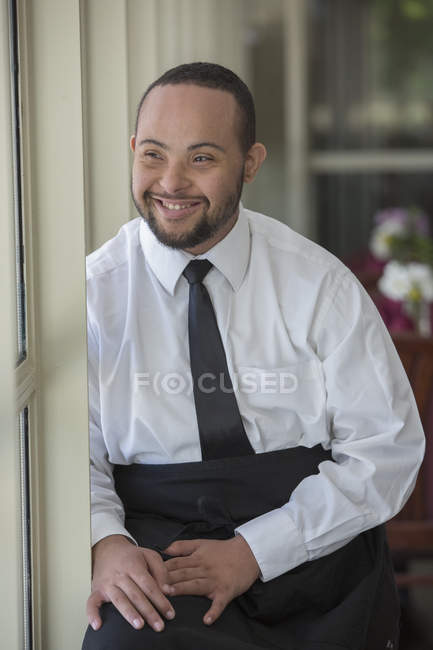 Happy African American man with Down Syndrome as a waiter in restaurant — Stock Photo