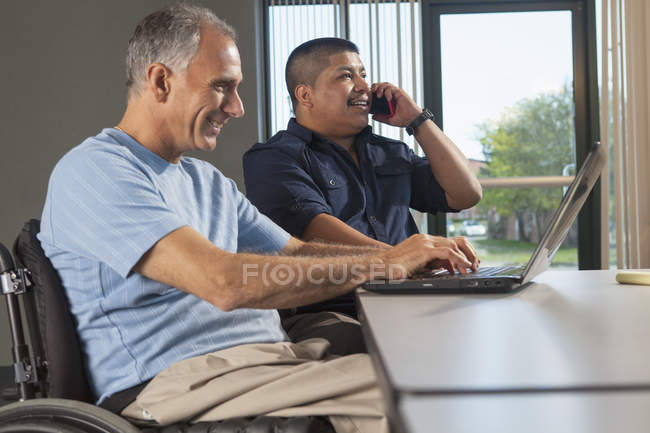 Dois homens com ferimentos na coluna vertebral a trabalhar num escritório — Fotografia de Stock