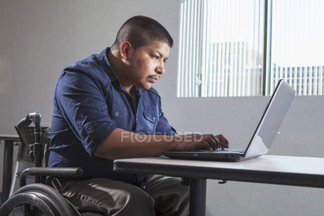 Латиноамериканец с травмой спинного мозга работает в офисе — стоковое фото