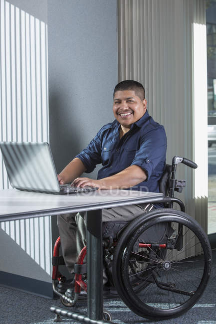 Латиноамериканец с травмой спинного мозга работает в офисе — стоковое фото