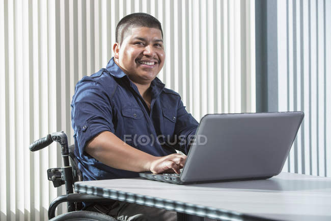 Homem hispânico com lesão medular trabalhando em um escritório — Fotografia de Stock
