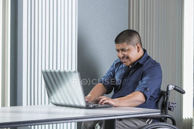 Homem hispânico com lesão medular trabalhando em um escritório — Fotografia de Stock