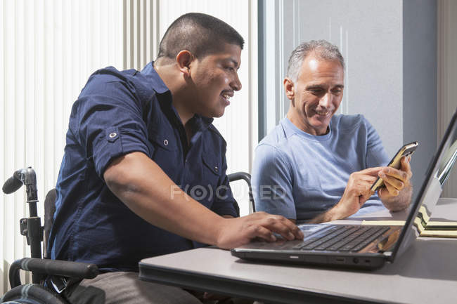 Двоє чоловіків з травмами спинного мозку працюють в офісі — стокове фото