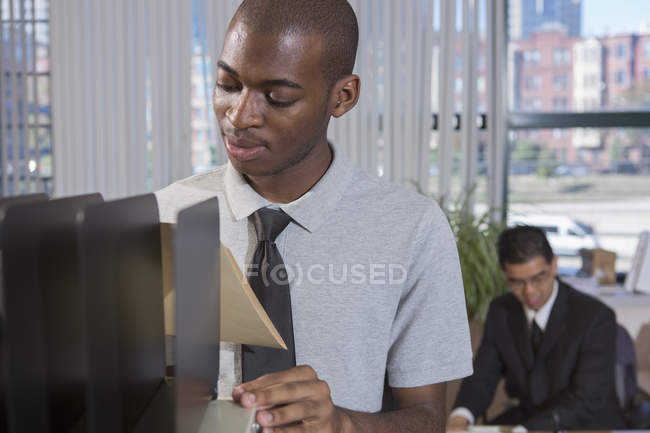 Hombre afroamericano con autismo trabajando en la oficina - foto de stock