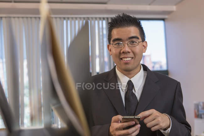 Asiatischer Mann mit Autismus arbeitet im Büro mit Smartphone — Stockfoto