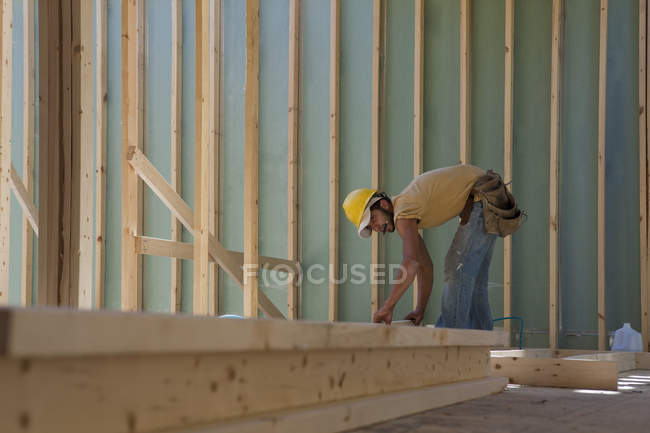 Carpinteiro colocando um parafuso prisioneiro em uma moldura de parede no local de construção do edifício — Fotografia de Stock
