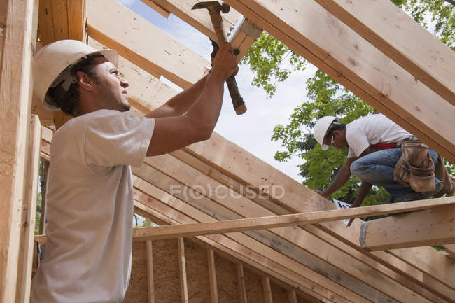 Zimmerleute montieren eine Dachlukenöffnung auf dem Dach eines im Bau befindlichen Hauses — Stockfoto