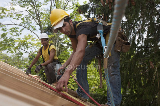 Charpentiers hispaniques mesurant dans une maison en construction — Photo de stock